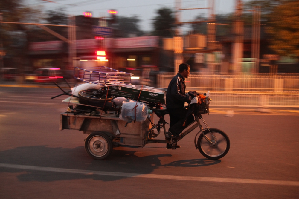 Mann fährt auf Motorrad mit Ladefläche in China