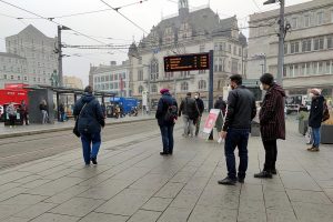 Menschen an einer Straßenbahnhaltestelle