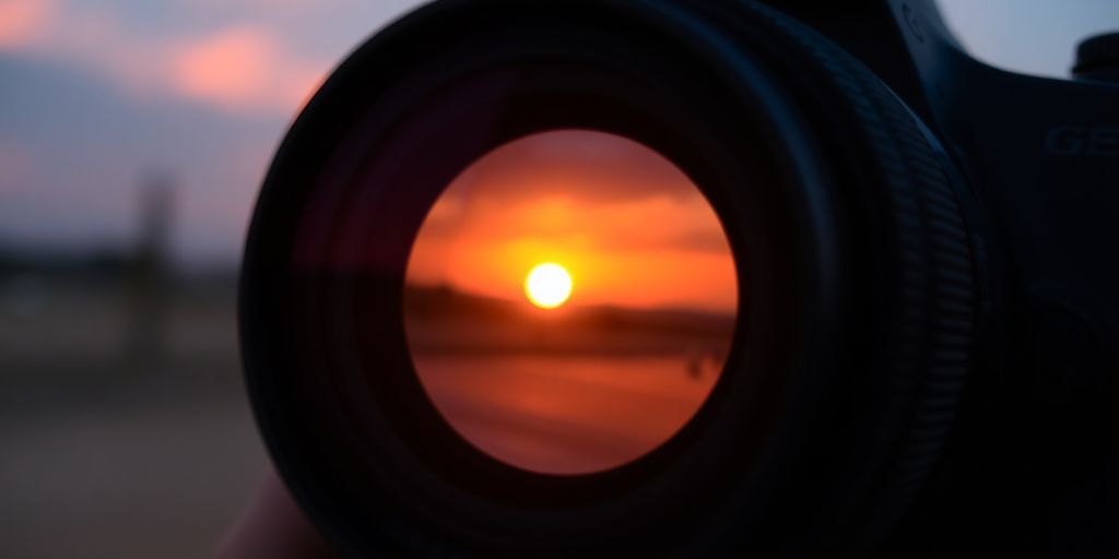 Nahaufnahme eines Kameraobjektivs mit Sonnenuntergang.